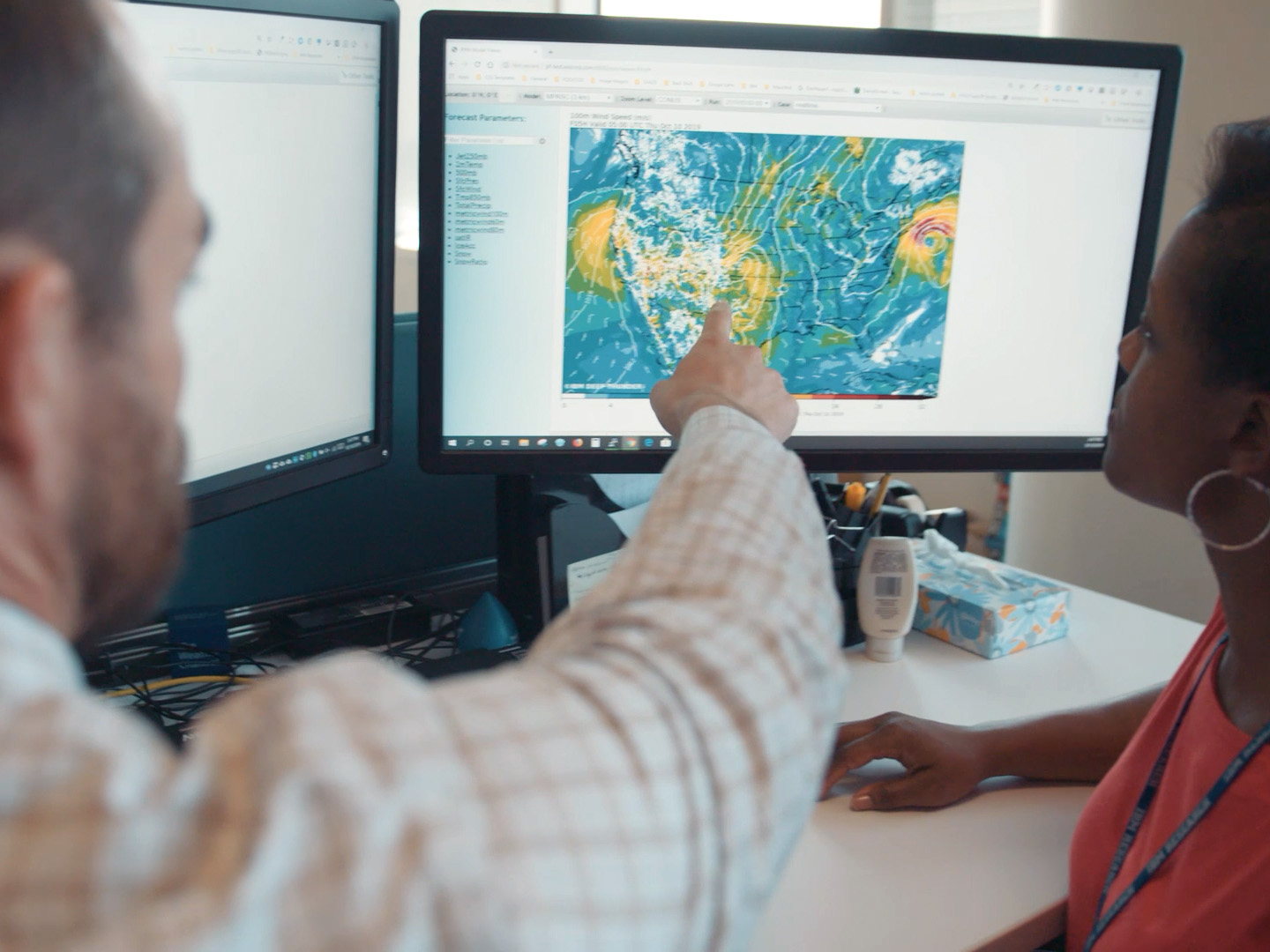 A person pointing at a weather map on a computer screen