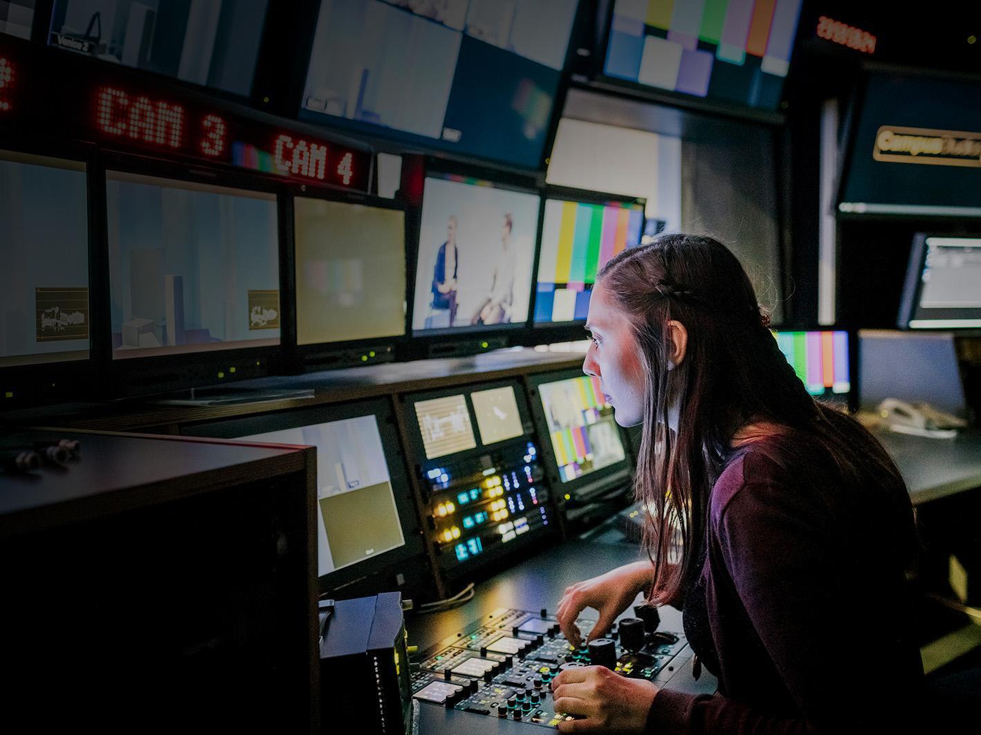 Weather forecasting producer in a studio looking at monitors.