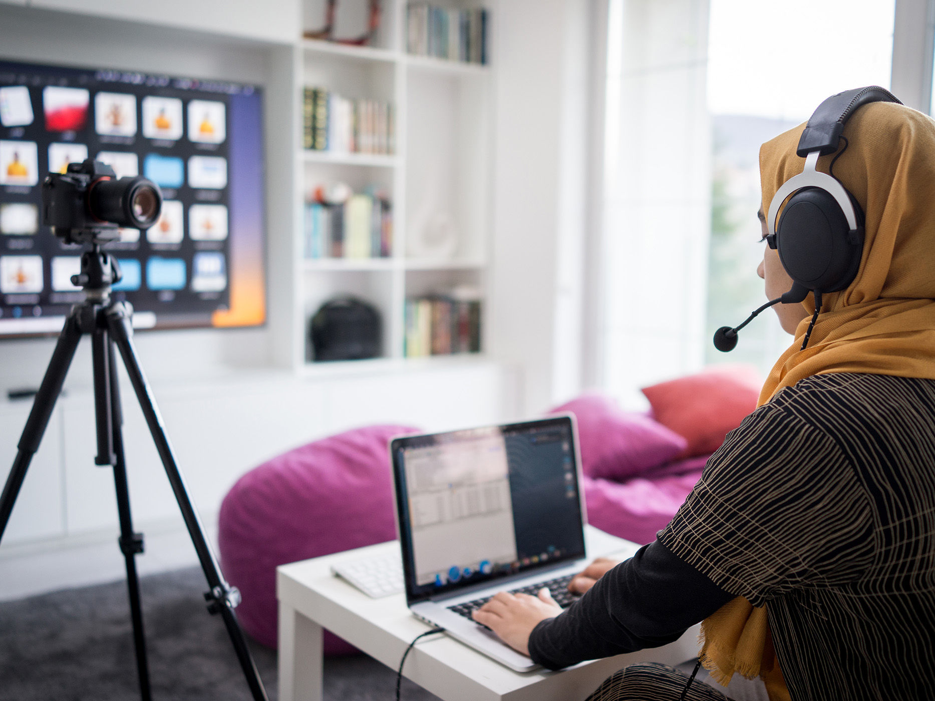 Person wearing headset sitting at laptop in front of camera