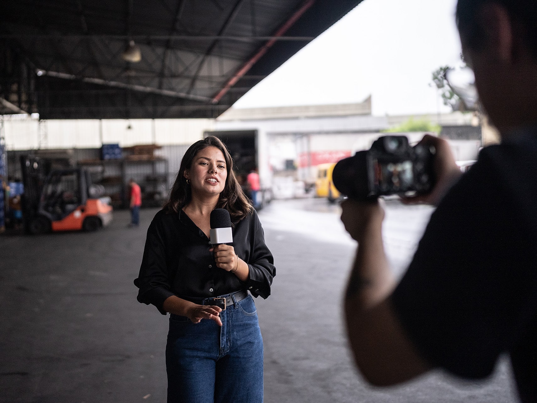 Woman holding a microphone and a person using camera