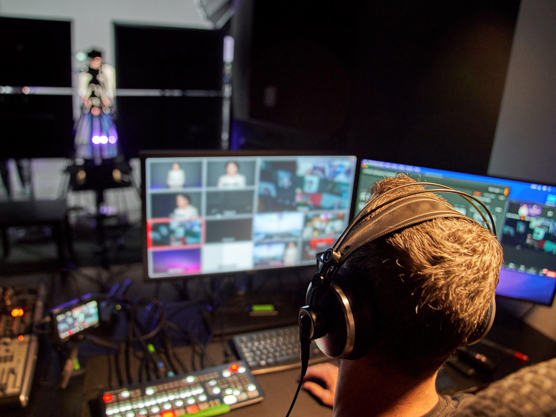 Person wearing headphones and monitoring video with multiple monitors