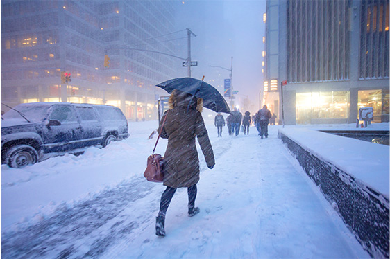 Person walking on a snowy sidewalk with umbrella