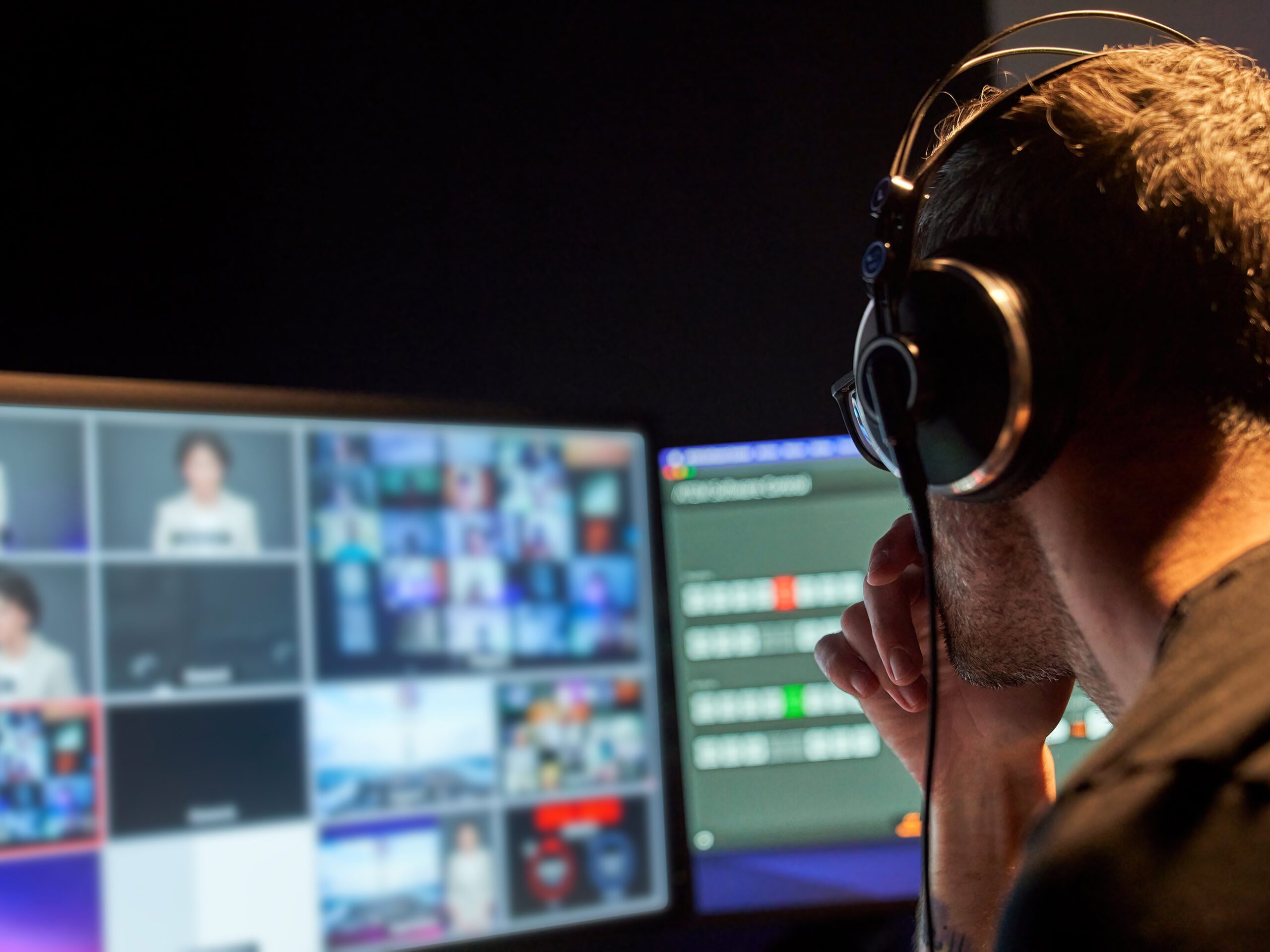 A male television producer editing video at a computer