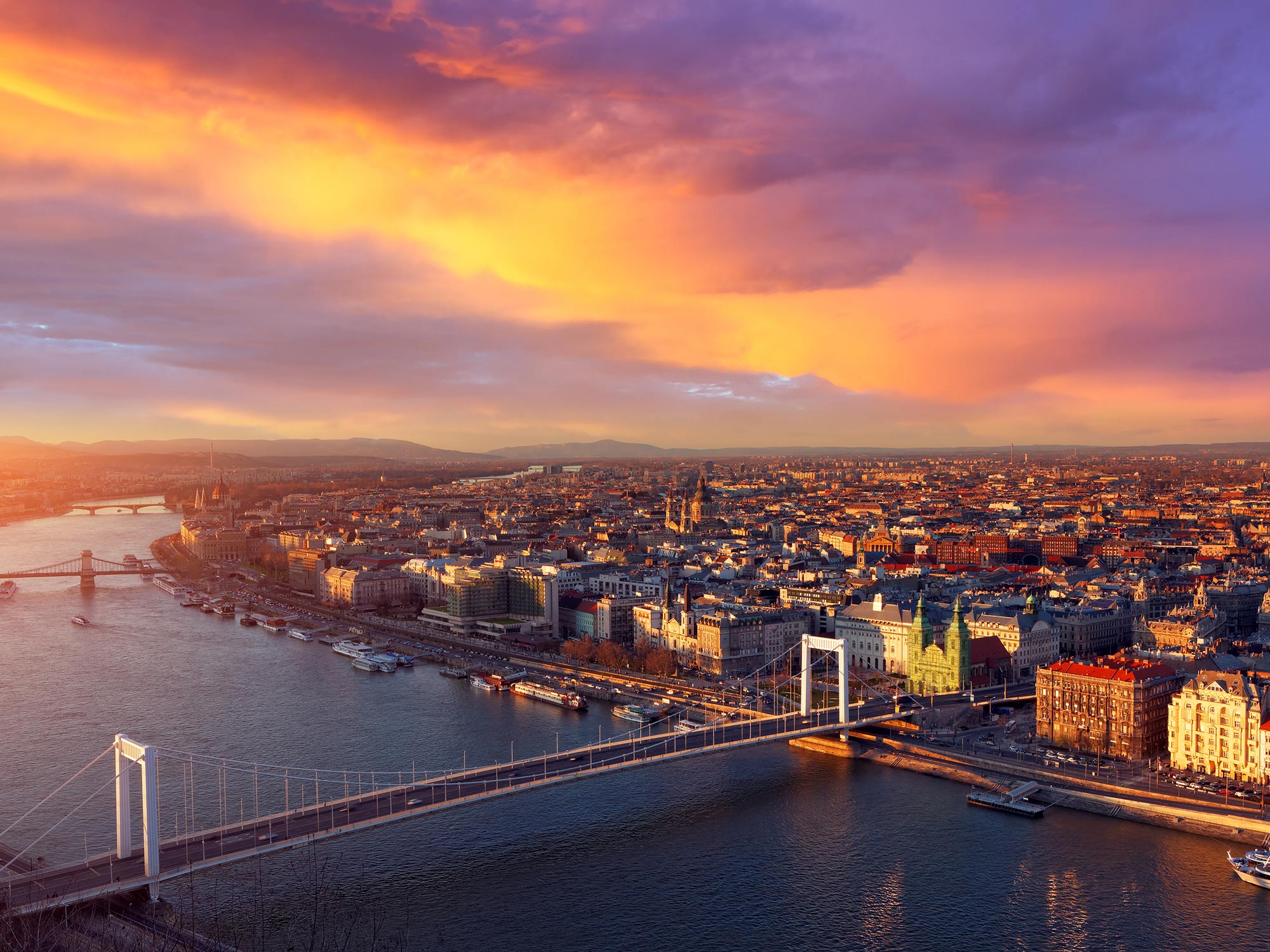 Budapest cityscape at sunset. The Elizabeth bridge is visible in the foreground.