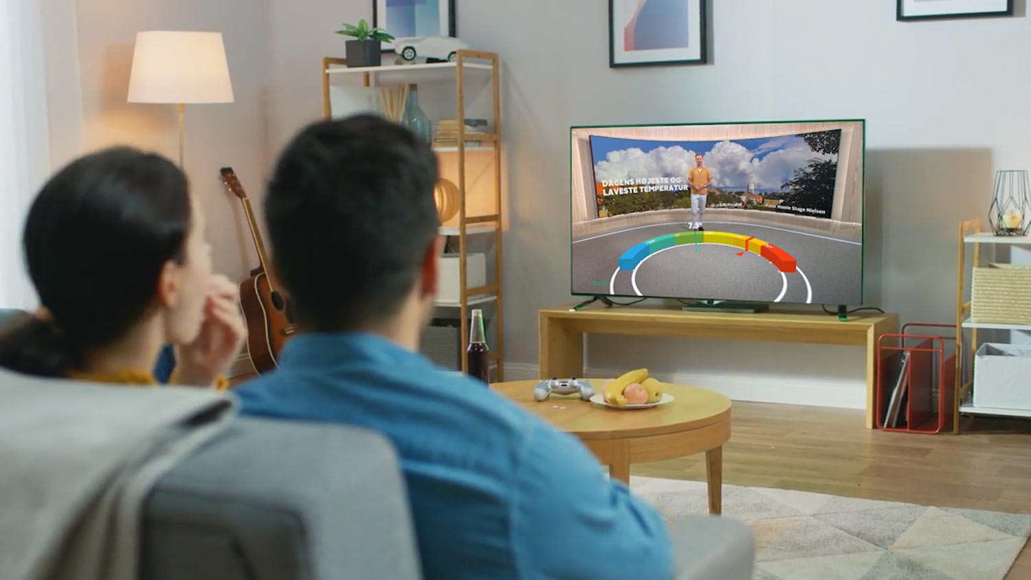 Couple on couch watching television showing weather report using Max Reality augmented reality graphics.