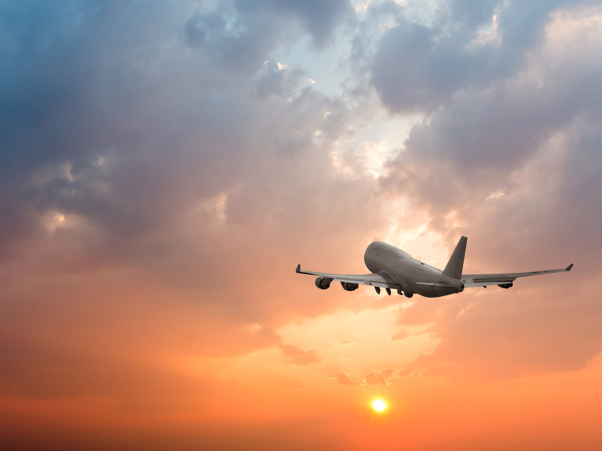 hero-aviation-airplane-flying-clouds-sunset-shutterstock_1104066083