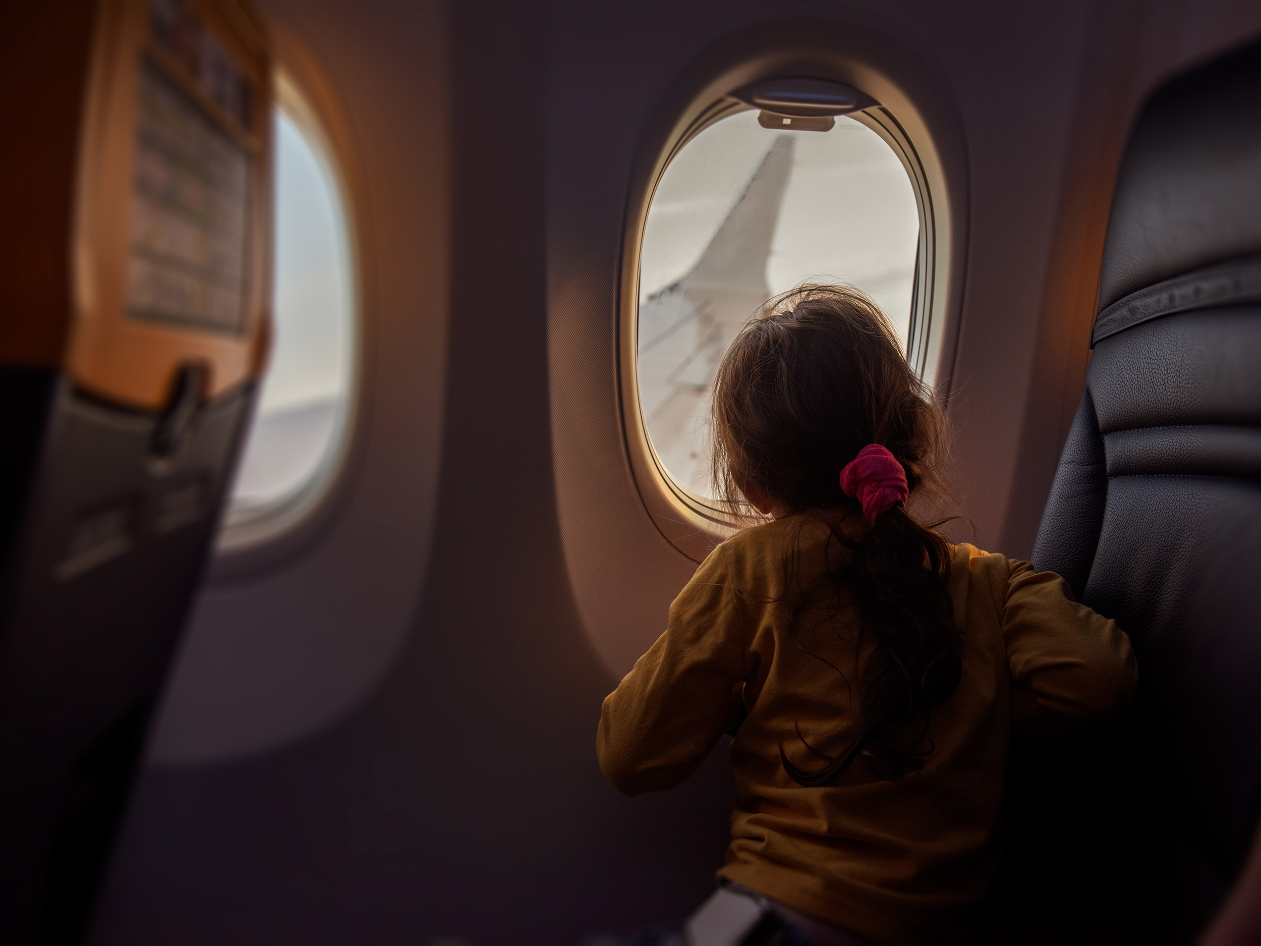 hero-aviation-girl-looking-out-airplane-window-GettyImages-1729080282