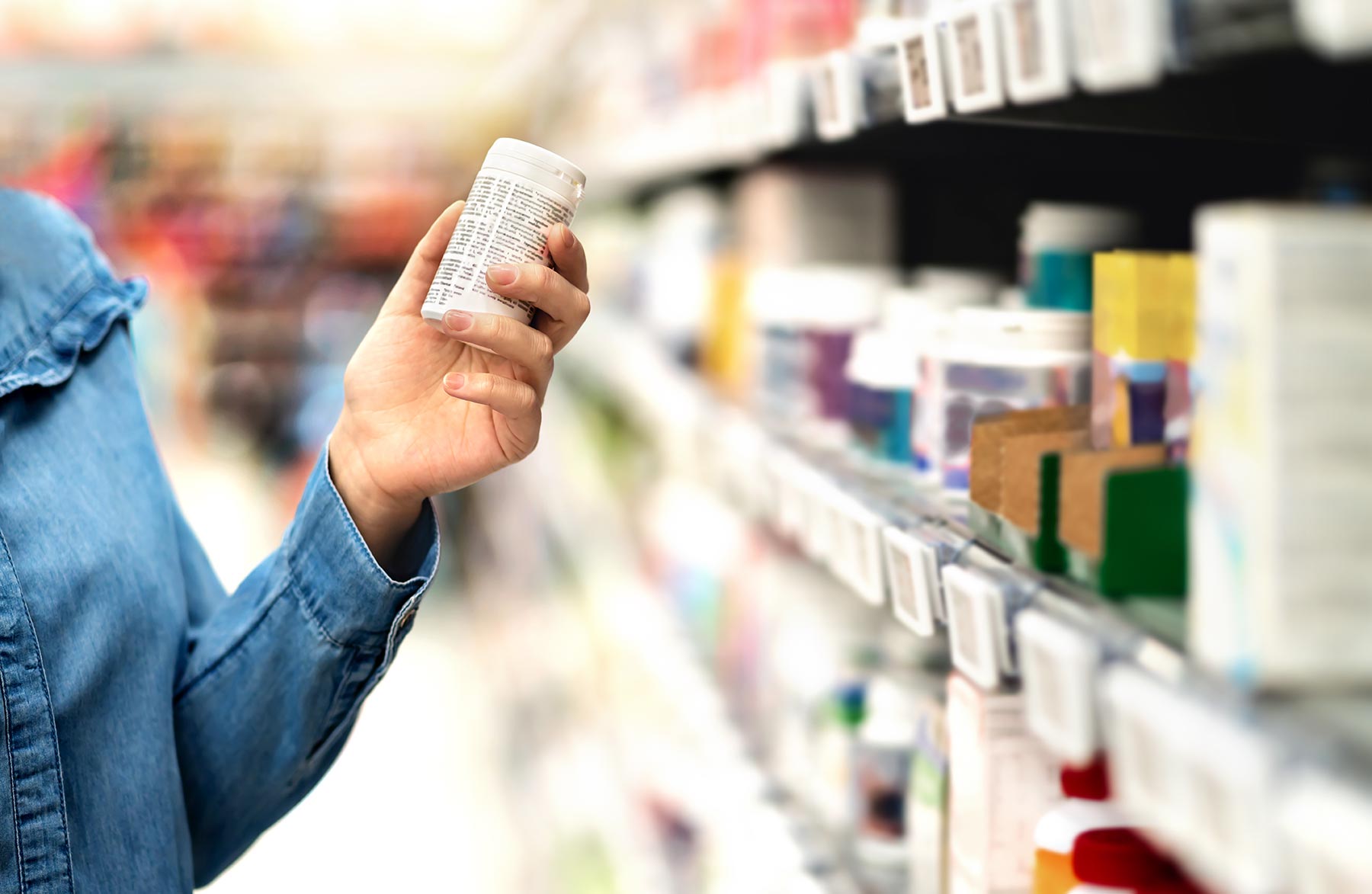 Hand picking medication off a pharmacy shelf.