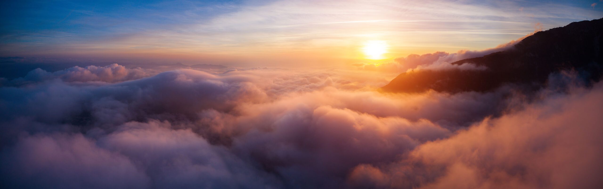 Beautiful sky over clouds around a mountain at sunset time.