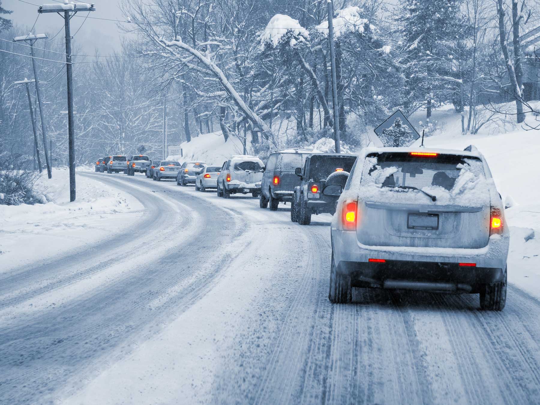 Cars in traffic curving around a road in the snow.