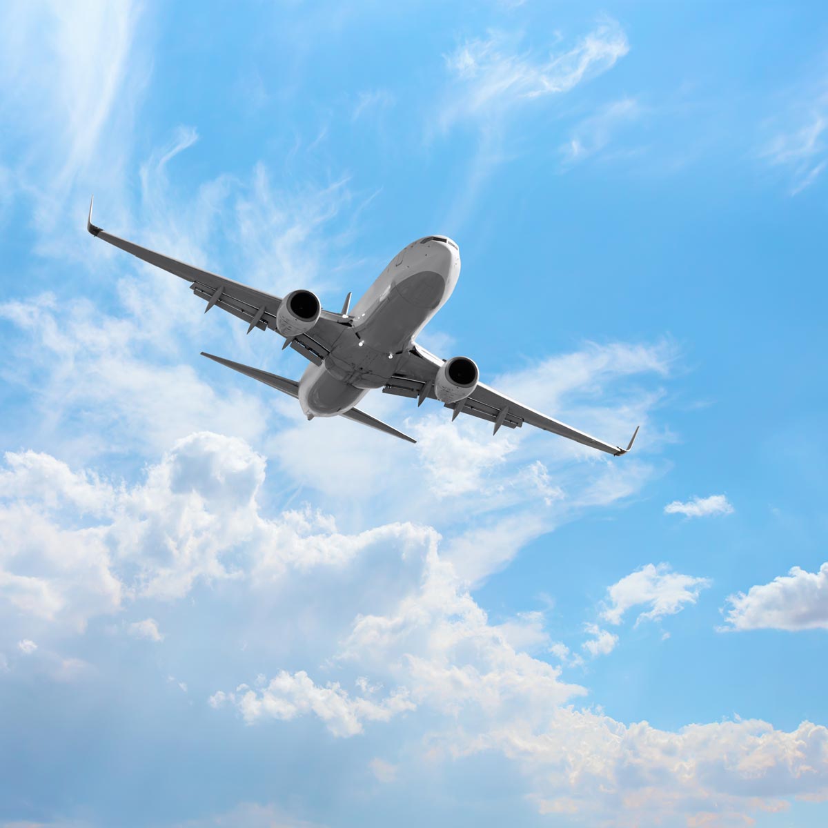 Airplane flying through a bluesky with white clouds