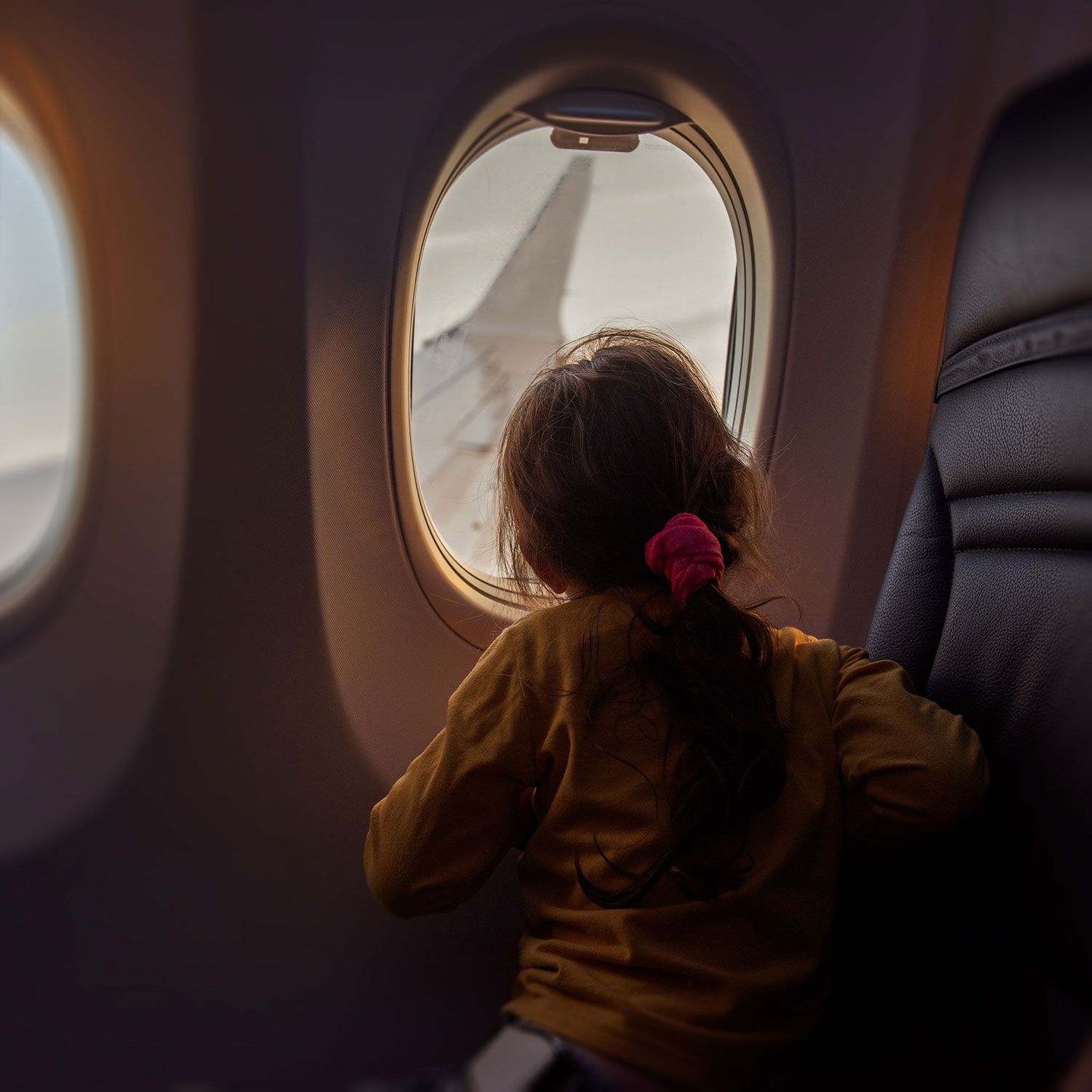 thumb-aviation-girl-looking-out-airplane-window-GettyImages-1729080282