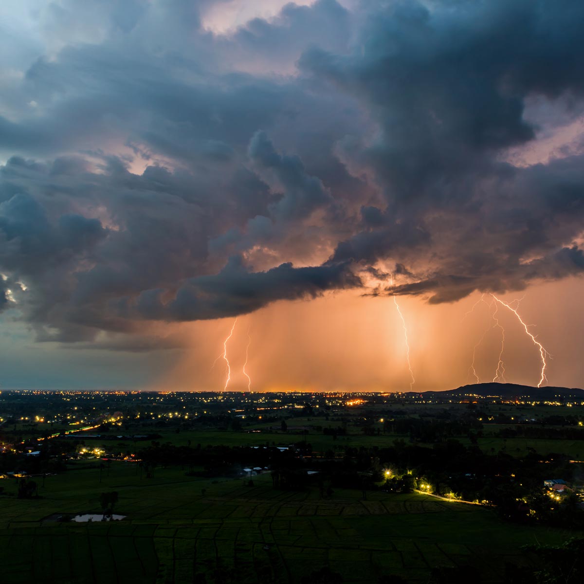 Lightning storm over a city with dark blue clouds.