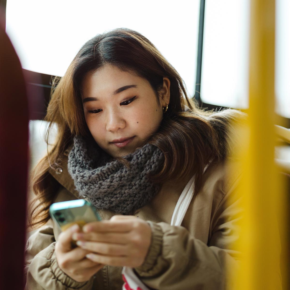 thumb-phone-asian-woman-bus-shutterstock_2241167933