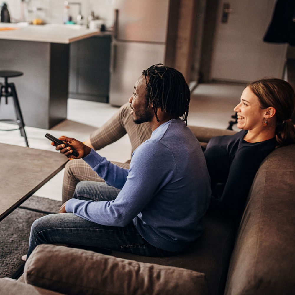 Couple sitting on couch watching television.