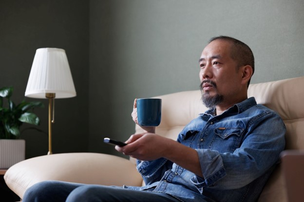 Man watching TV with coffee cup flipping the channel