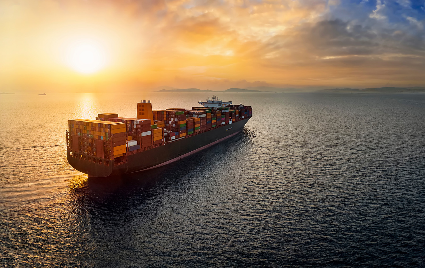 Cargo ship sailing on smooth seas at sunset