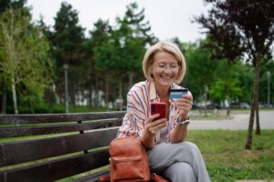 Woman outdoors making a purchase on a mobile phone.