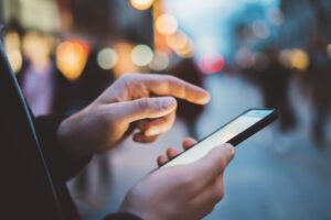 Closeup of male hands tapping on a smartphone outside