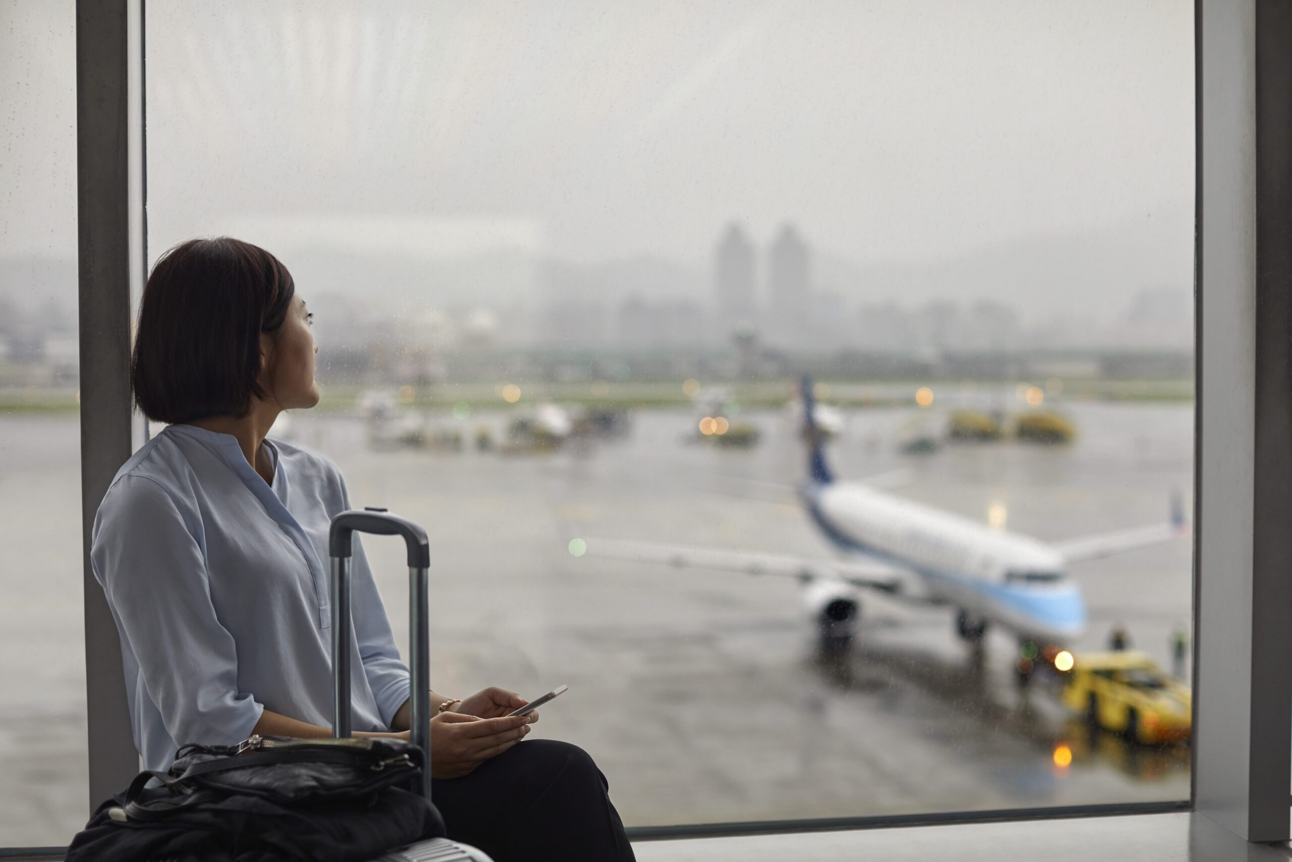 Woman looking out a rainy window at an airport