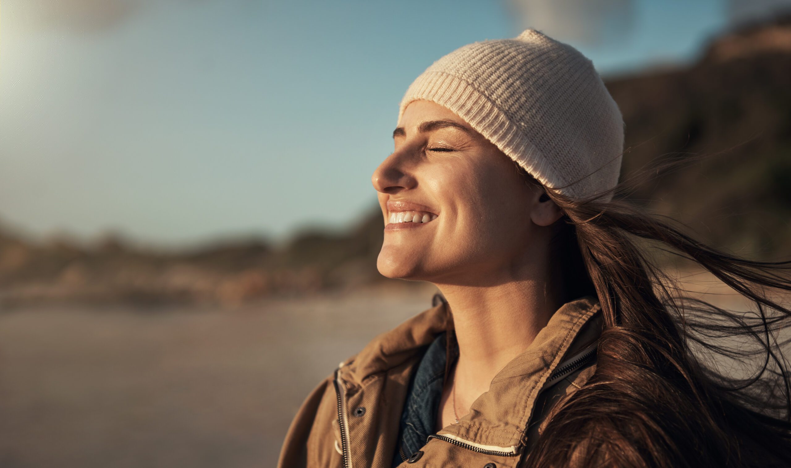 Cropped shot of an attractive young woman standing alone and enjoying the sunset on the beach