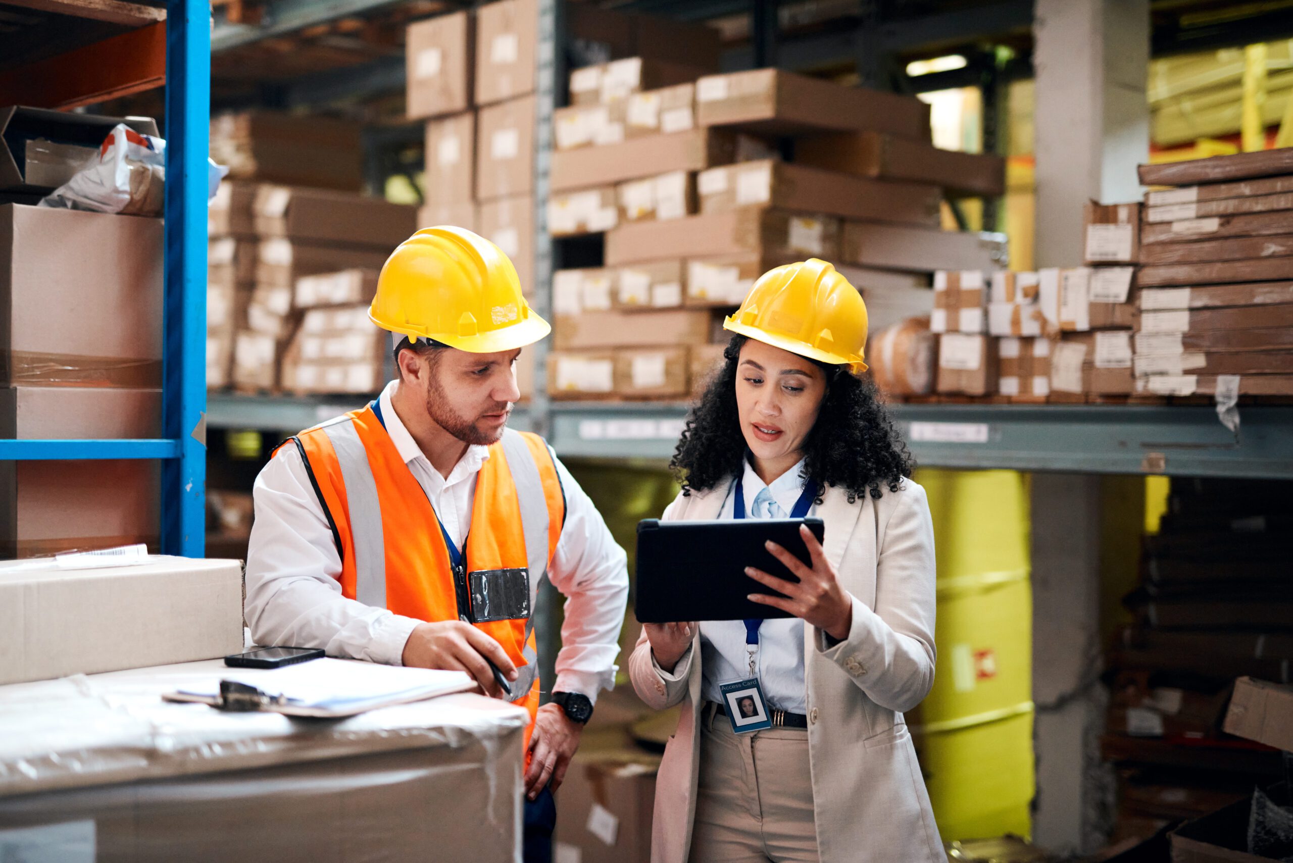 Warehouse employees monitor supply chain updates on a tablet.