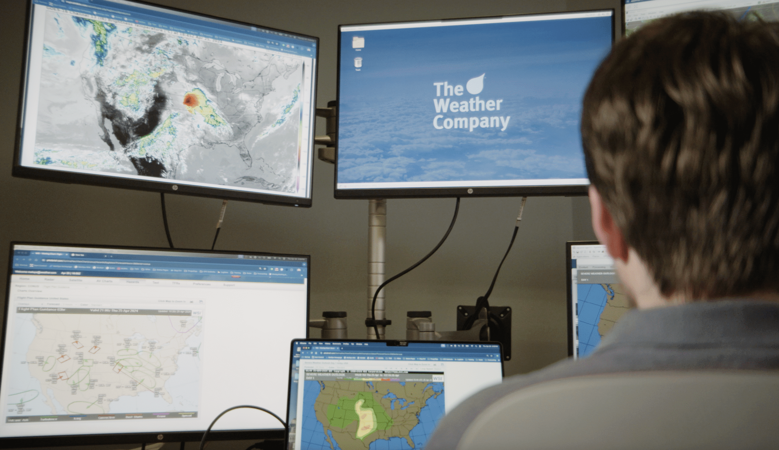 Meteorologist looking at screens with weather forecasts and data