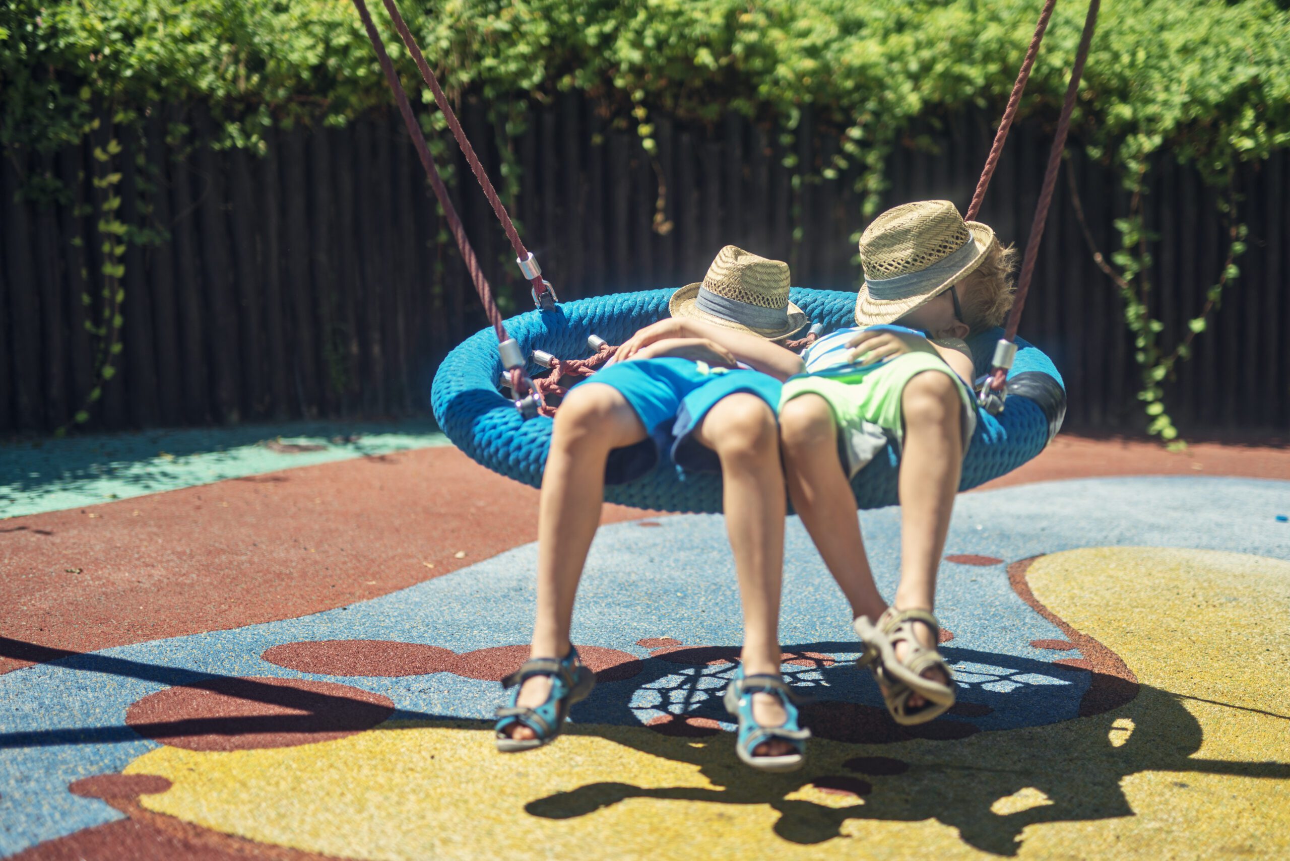 Two boys on a lazy, hot summer day. Kids are lying on on a big swing on the playground and sleeping. Example of the Cocooning mindset in Mindset Marketing