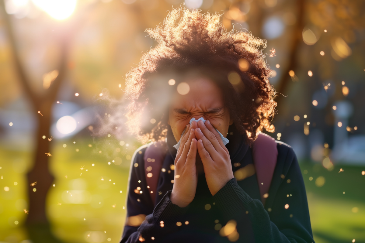 A woman outdoors sneezing from pollen irritation