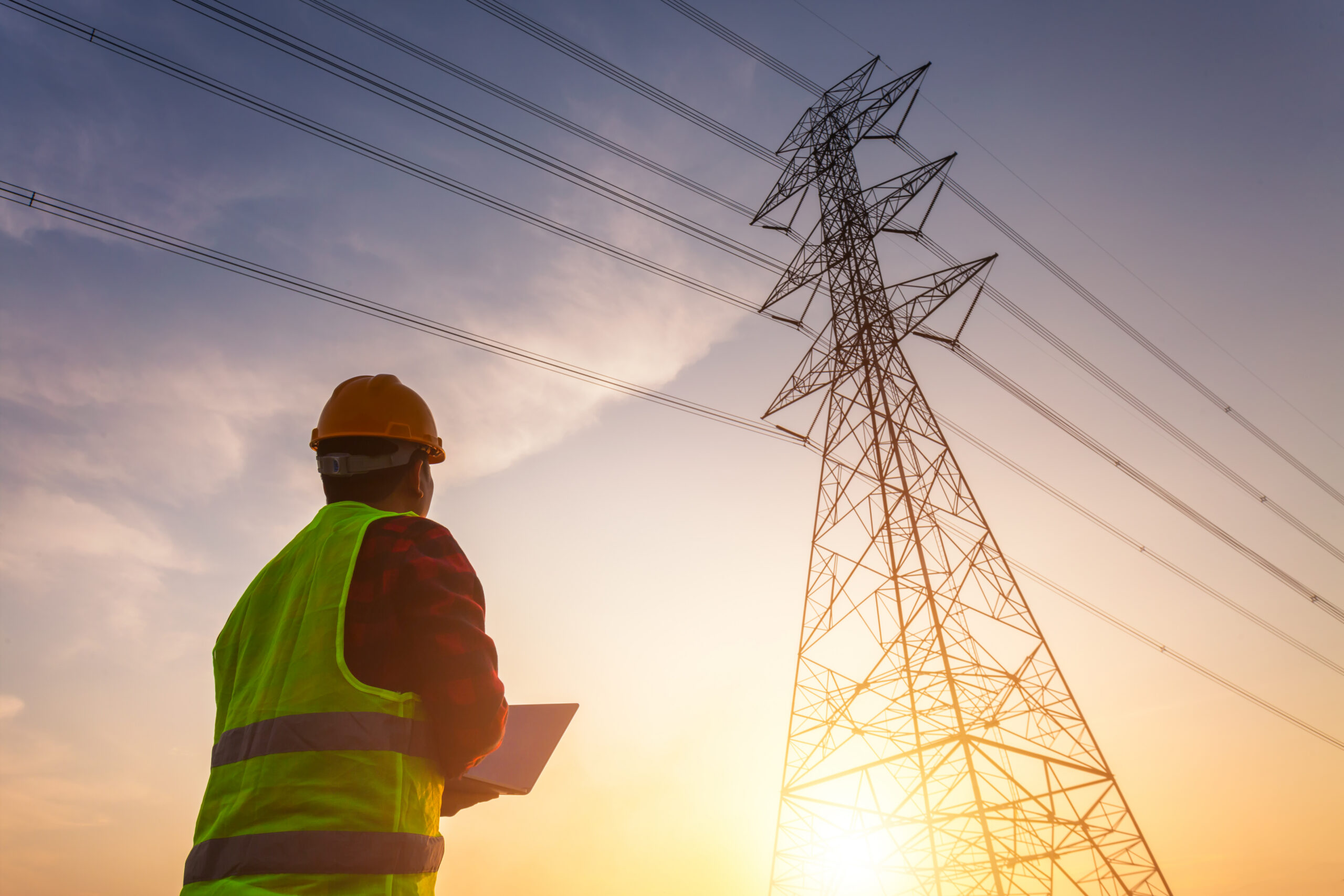 Utilities worker in standard safety uniform working to inspect the electricity high voltage pole.