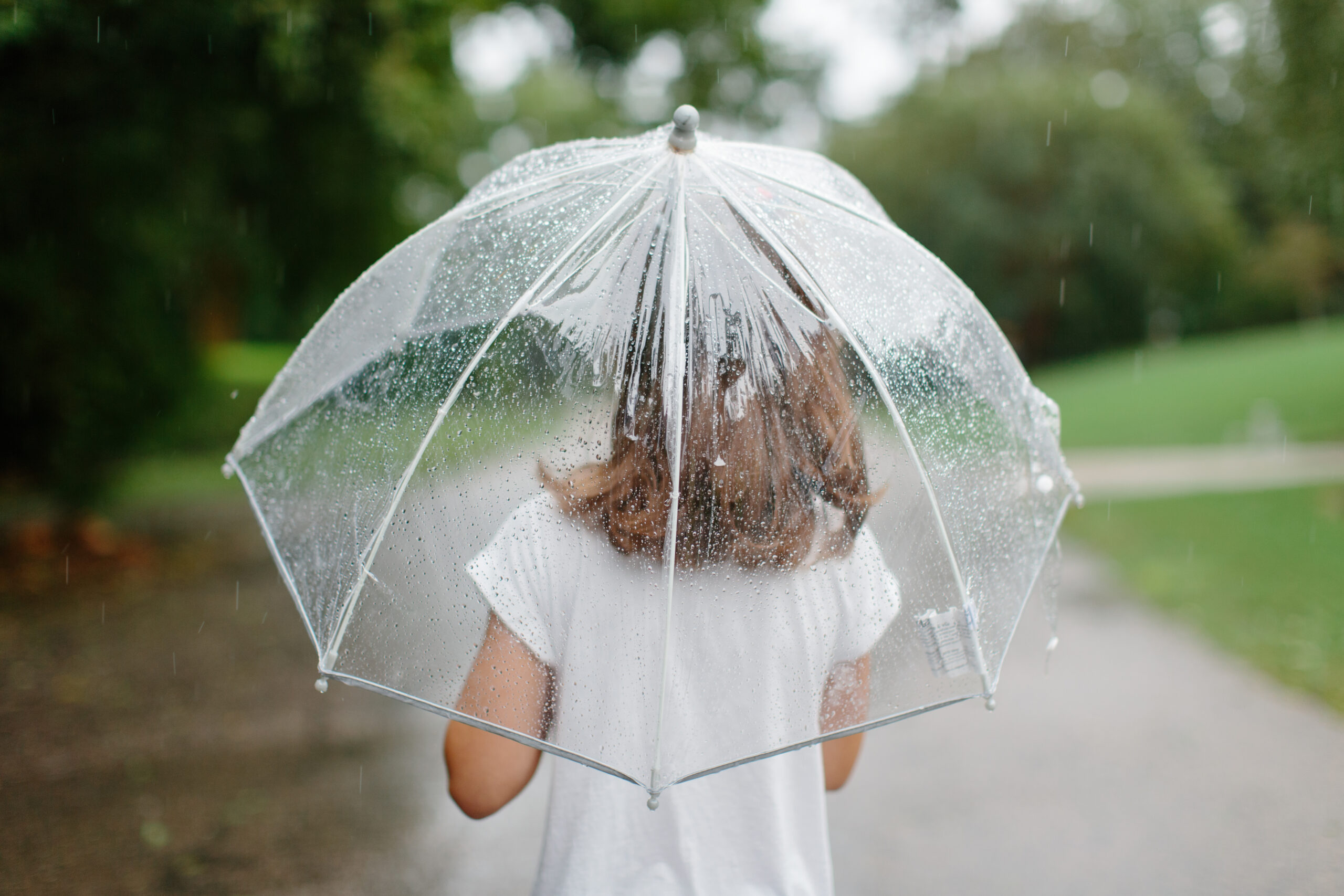 Girl walking in rain with clear umbrella